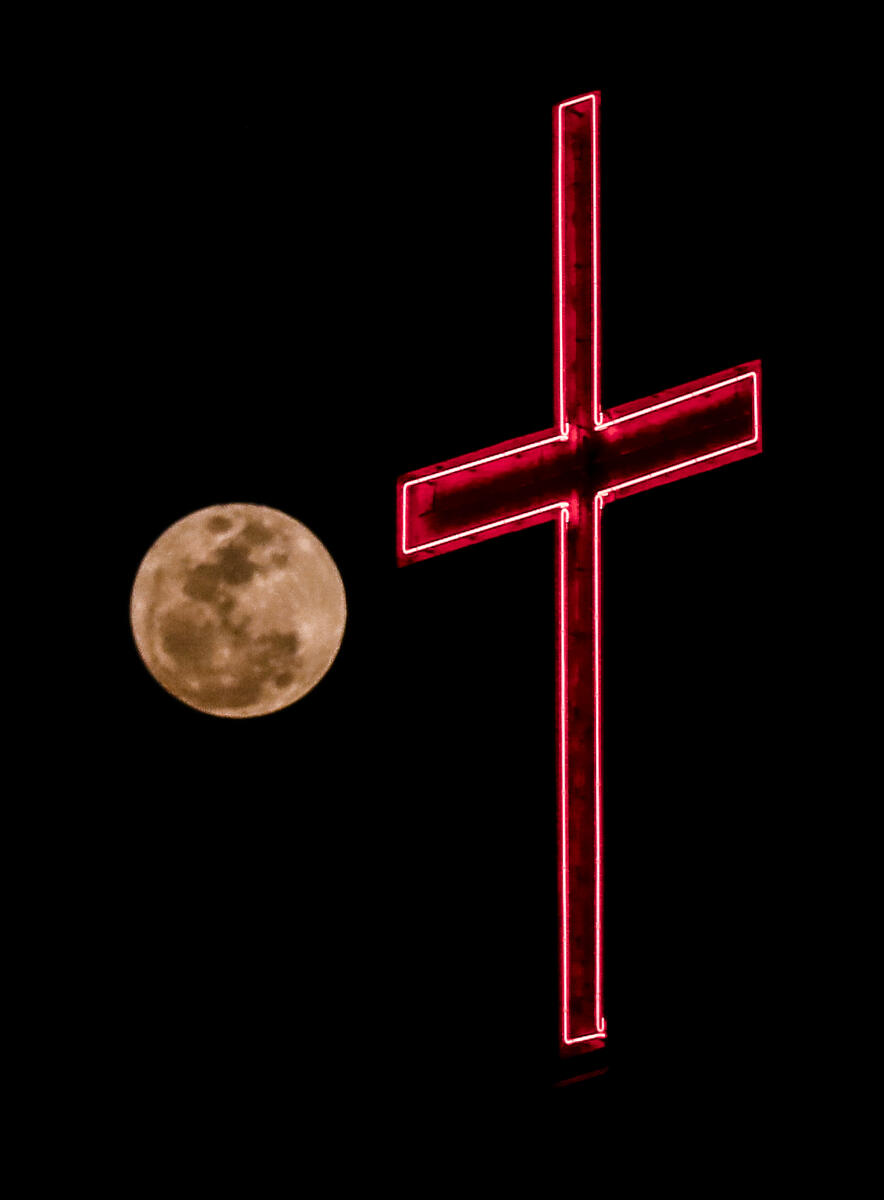 The full moon rises behind a cross symbol on the occasion of 'Buddha Purnima' festival, in Hyderabad, Telangana, Friday, May 1, 2026.