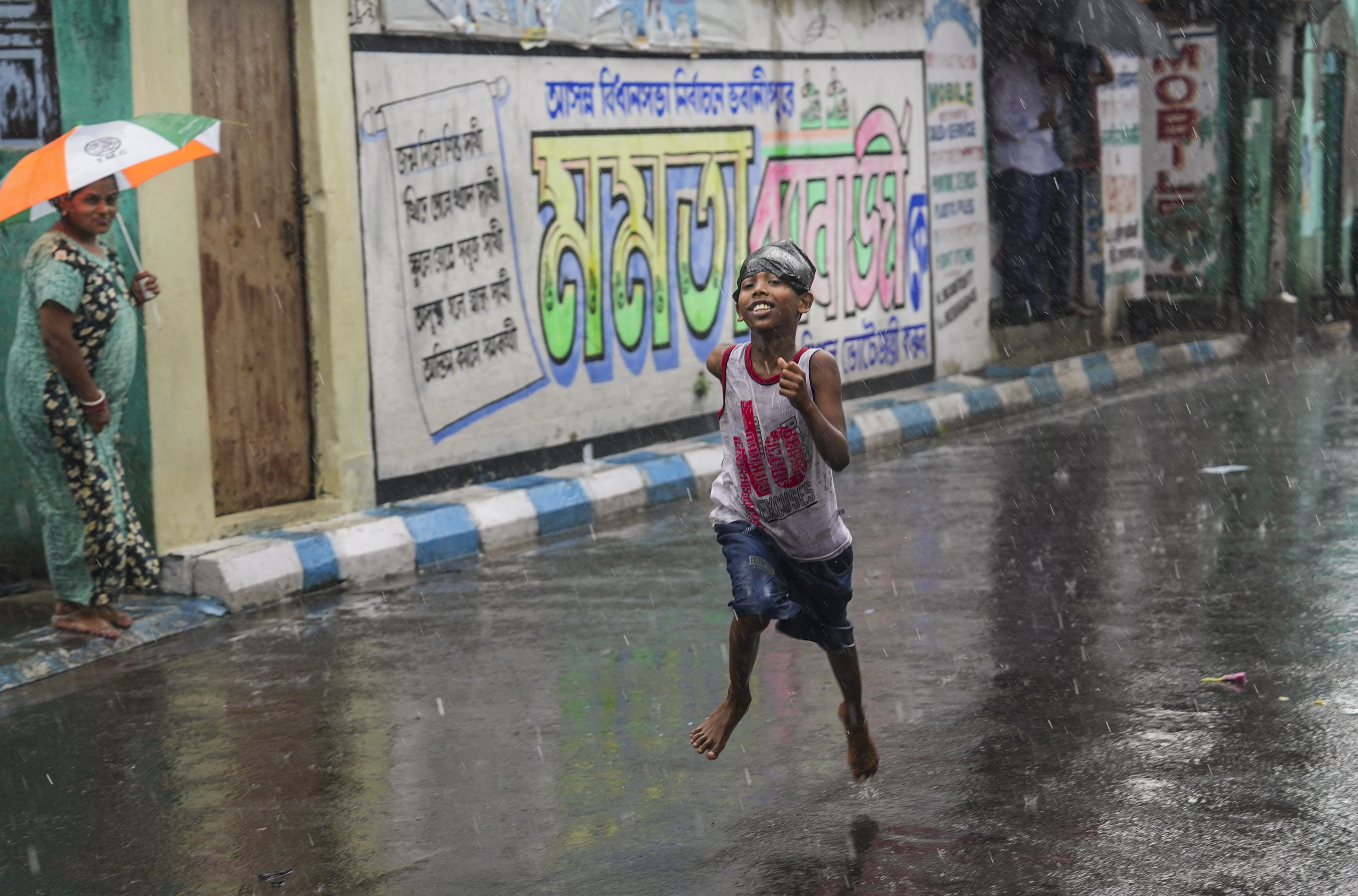 A boy runs amid rain, in Kolkata