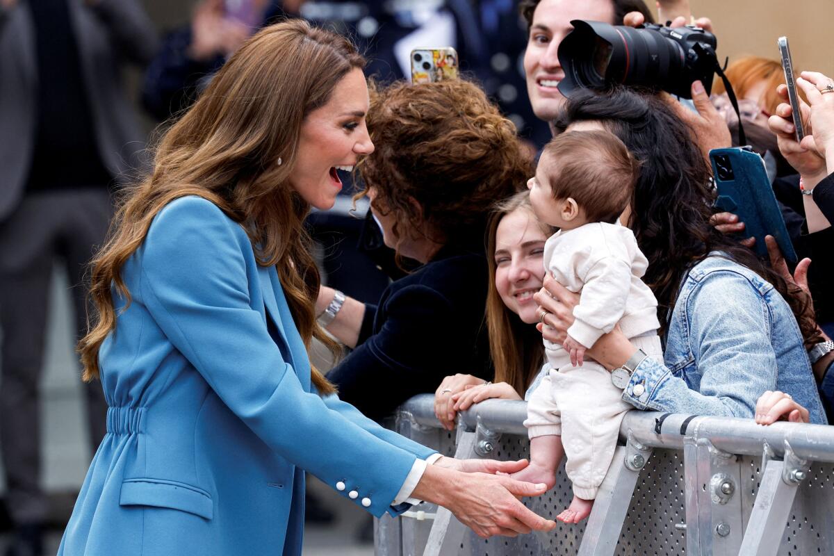 Britain's Kate, Princess of Wales, interacts with a baby after visiting Reggio Emilia town hall in Italy.