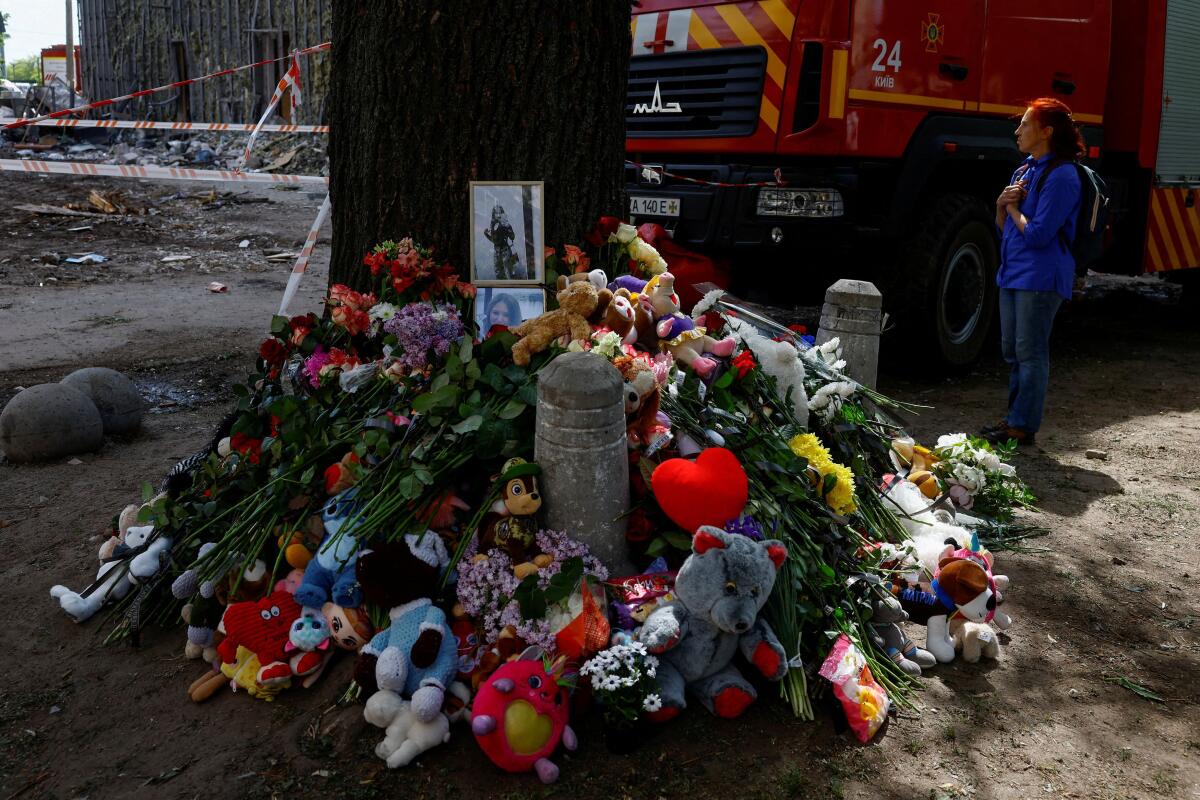A woman reacts next to a makeshift memorial at the site of an apartment building where 24 residents were killed yesterday morning by a Russian missile strike in Kyiv, Ukraine.