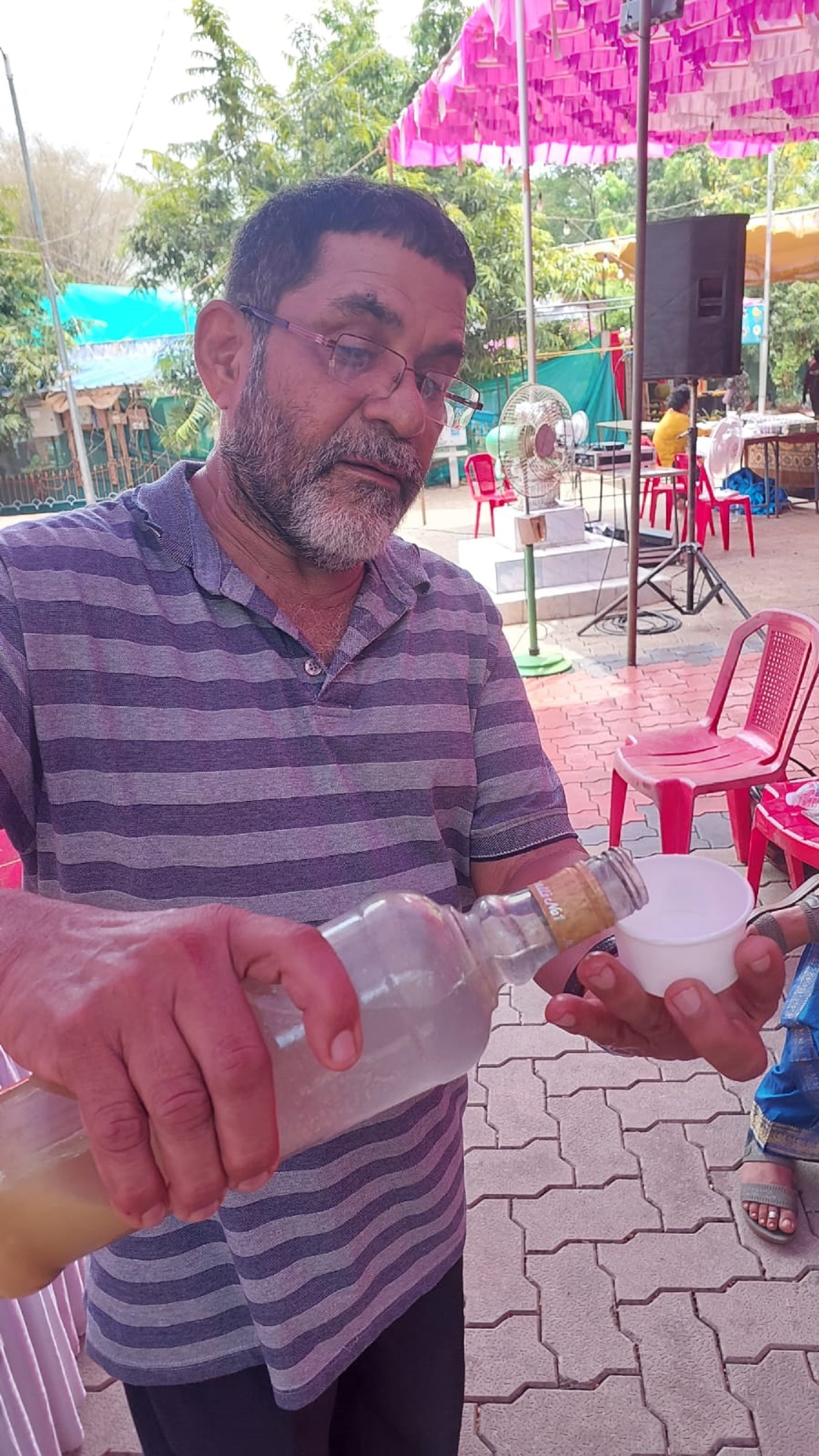 Shyam Bhat offers home-made cashew apple juice to a guest. DH Photo/ Fakruddin H