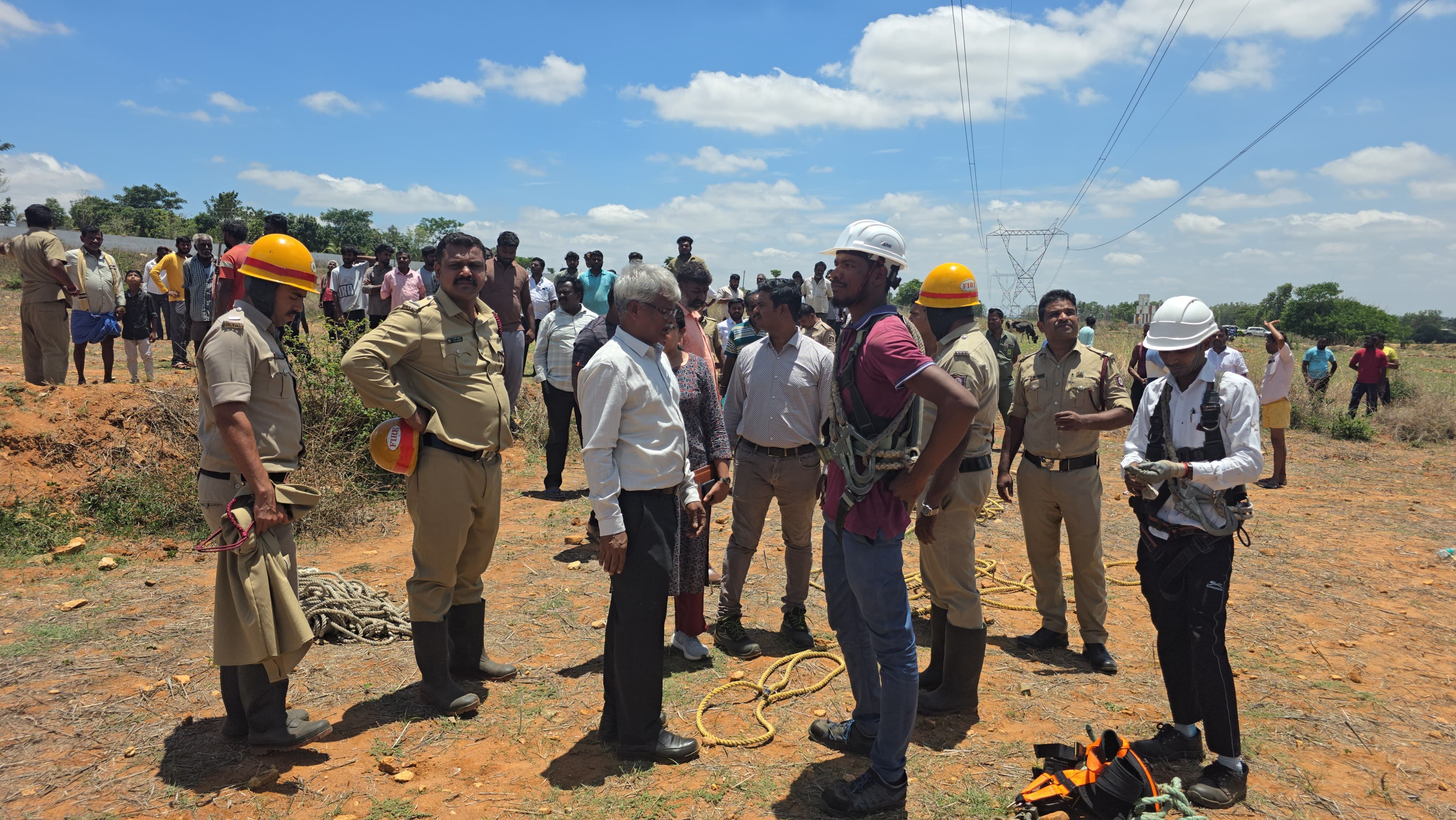 Fire and Emergency Services personnel and locals gather near the high-tension tower during the rescue operation.