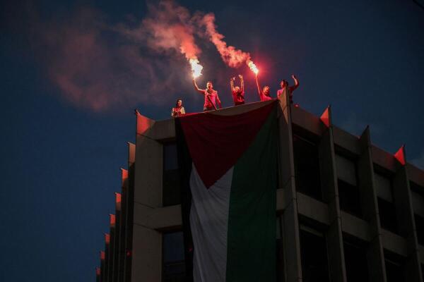 Protesters who hung a huge Palestinian flag at a building facing the Israeli embassy, lit flares during a protest over the interception of the Gaza aid flotilla, in Athens, Greece