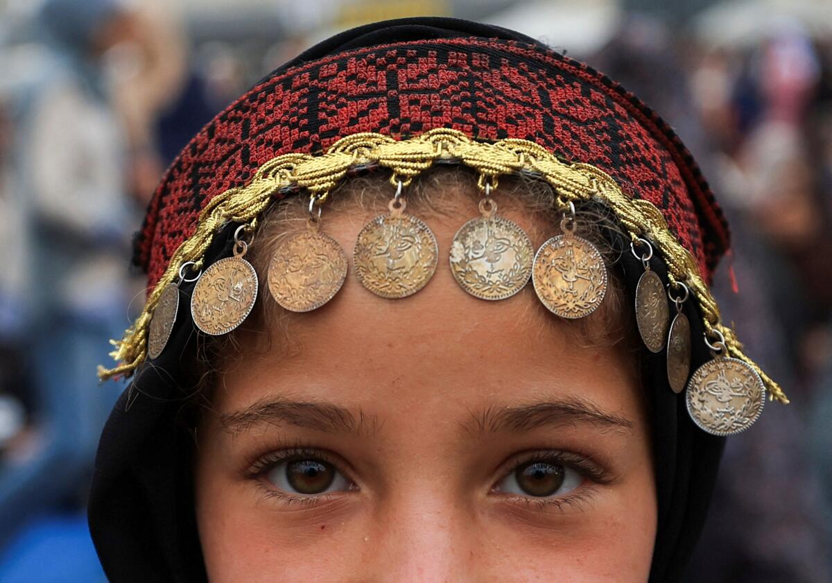 A Palestinian girl, wearing traditional headwear, poses for a photograph on Eid al-Adha, in Gaza City.