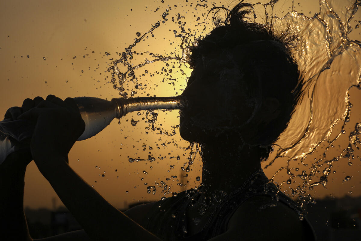 A young man splashes water on his face to beat the heat on a hot summer day, in Jammu.