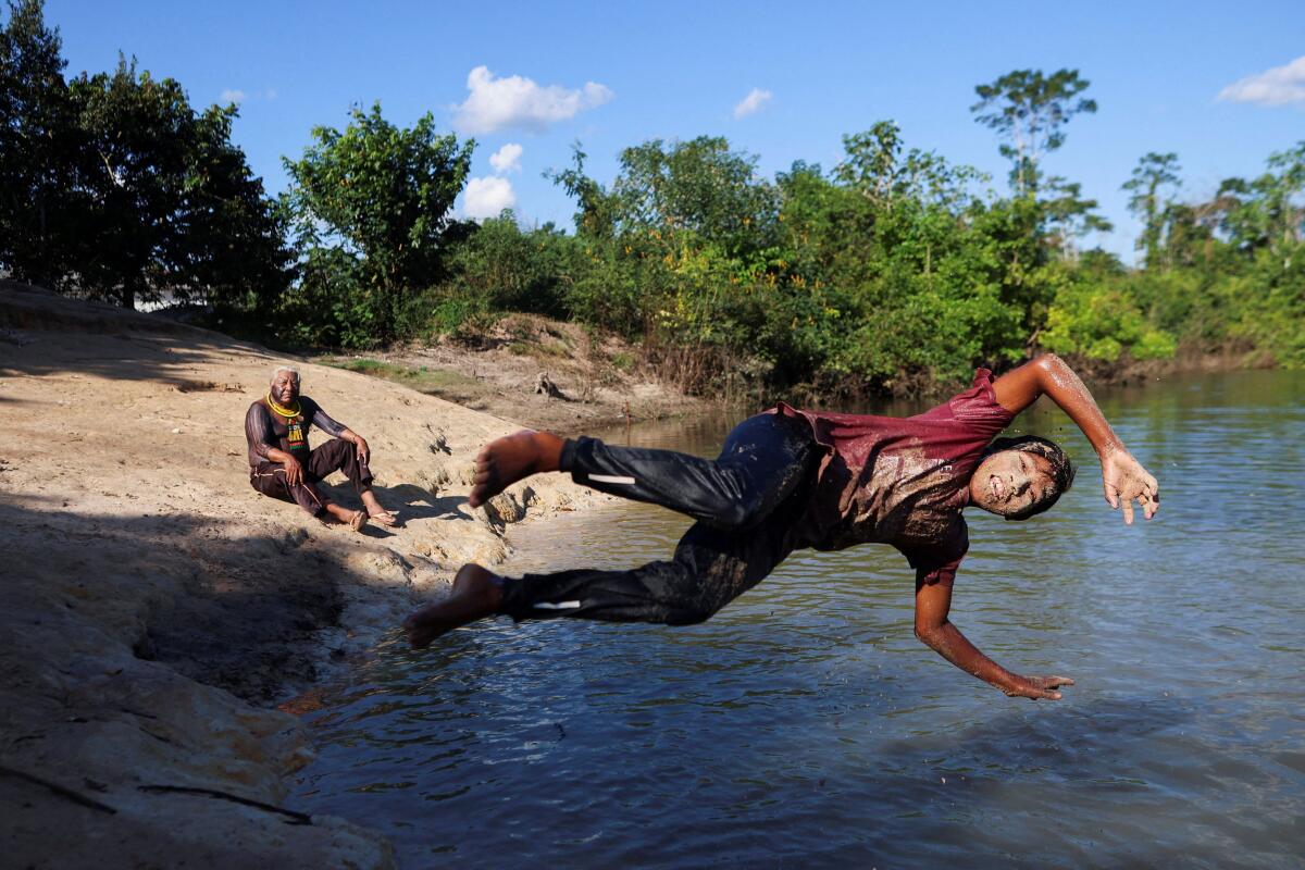 Indigenous leader Megaron Txucarramae interacts with children playing in a river while attending an interview with Reuters in the village of Pykany in the Menkragnoti Indigenous Territory of the Kayapo people, Para state, Brazil.