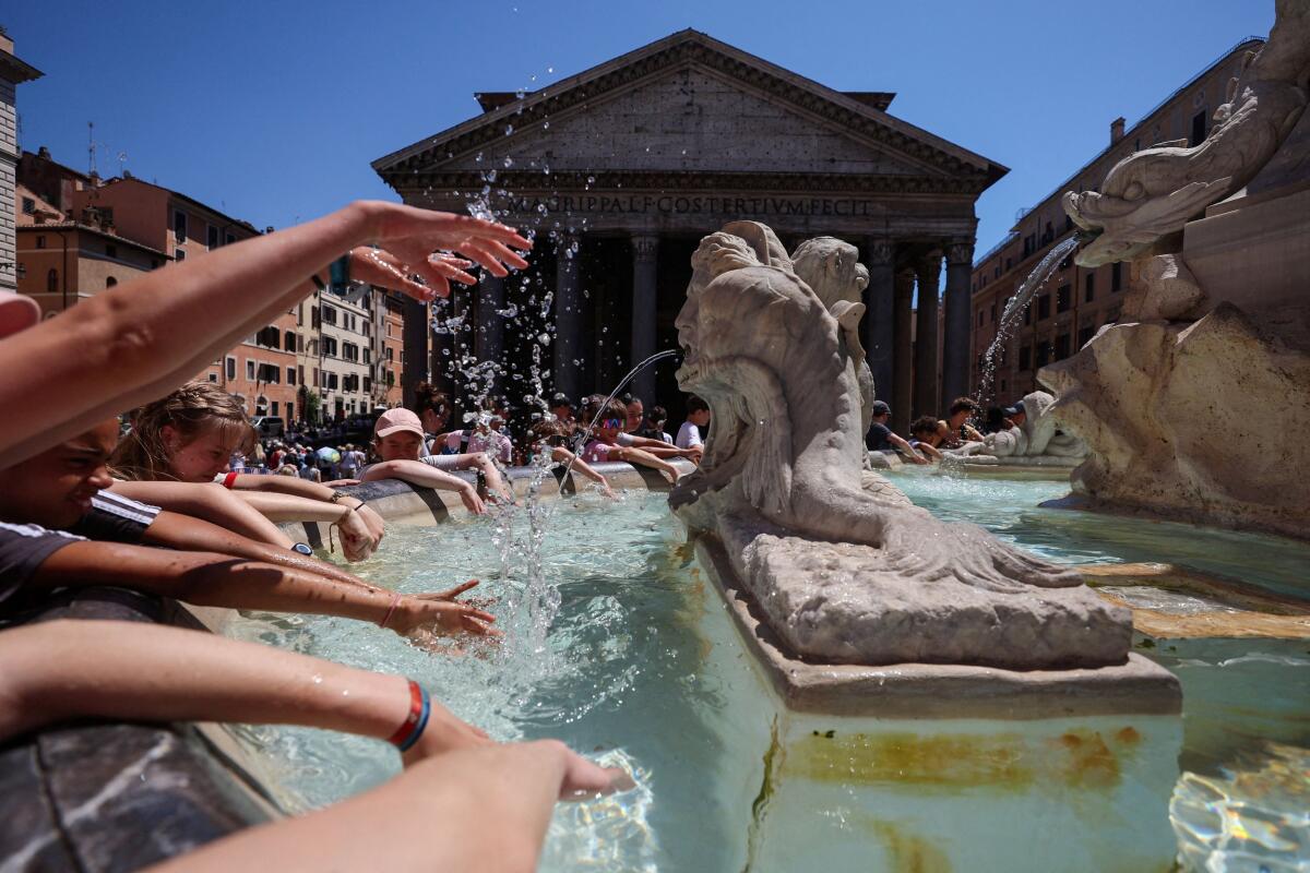 Tourists cool off at a fountain near the Pantheon during a heatwave in Rome, Italy.