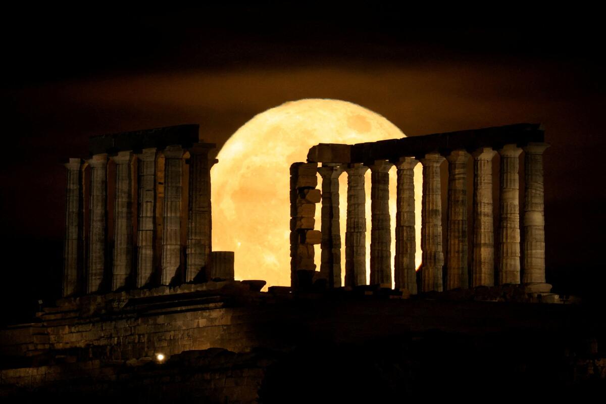 A full moon known as the "Blue Moon" rises behind the Temple of Poseidon, in Cape Sounion, near Athens, Greece.