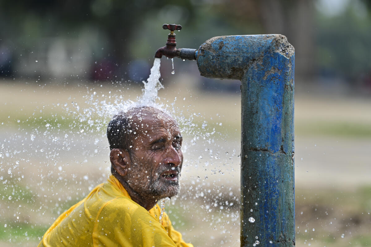 A man tries to cool himself under running tap water amid scorching summer heat, in Prayagraj, Uttar Pradesh