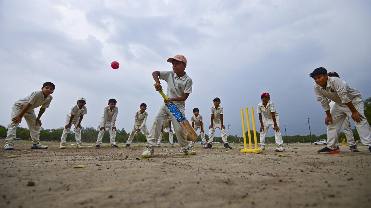 Young boys practice cricket as dark clouds hover over the horizon, in Prayagraj, Uttar Pradesh.