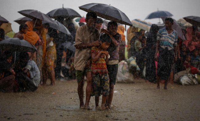 Rohingya refugees try to take shelter from torrential rain as they are held by the Border Guard Bangladesh (BGB) after illegally crossing the border, in Teknaf, Bangladesh, August 31, 2017. REUTERS/Mohammad Ponir Hossain