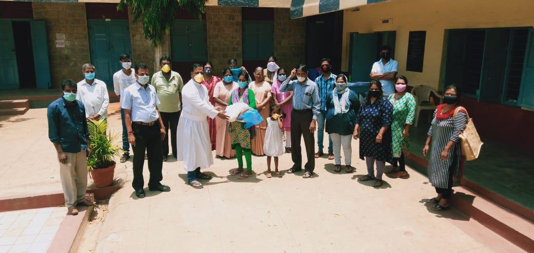 A beneficiary receiving provisions from Rev Dr John Mathew together with the other volunteers who helped in the drive