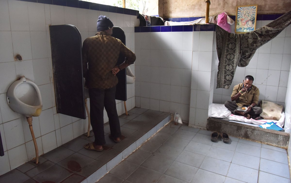 A man uses a corner of the public toilet at Shivananda Circle to eat, while a man finishes his business nearby. This picture was taken on Tuesday.