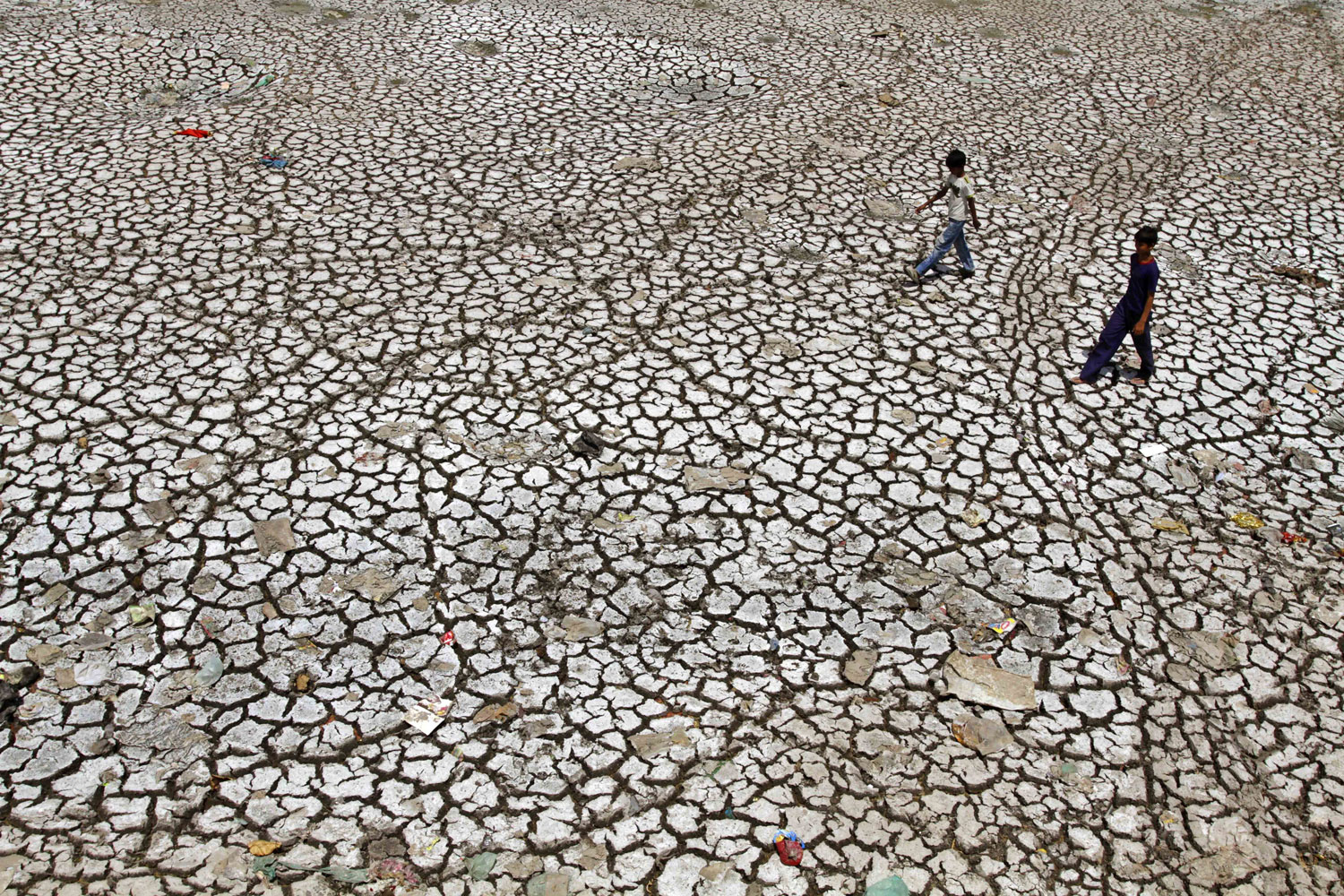 Boys walk on a parched portion of the River Sabarmati in Ahmadabad, on Monday. Huge swathes of rural farmland has turned dry as farmers await the annual  monsoon rains which, according to the India Meteorological Department, are  expected to reach on...