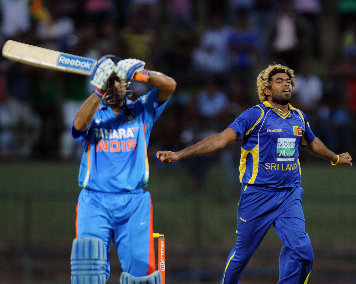 Sri Lankan cricketer Lasith Malinga (R) celebrates after dismissing Indian cricket team captain Mahendra Singh Dhoni (L) during the fifth and final one-day international (ODI) match between Sri Lanka and India at the Pallekele International Cricket S...