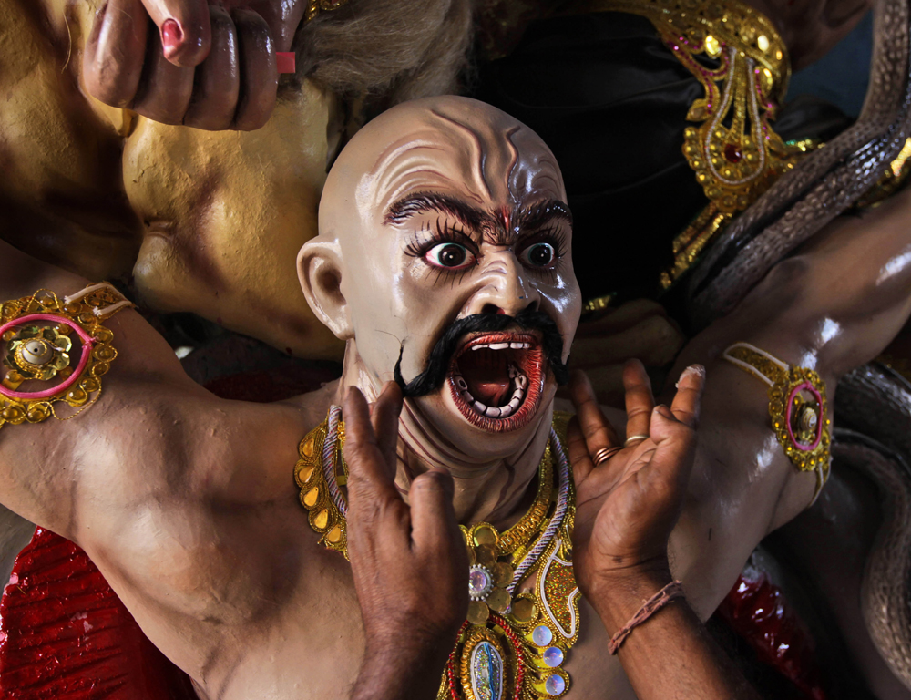 An Indian artist pastes mustaches on to a clay model of a devil for the upcoming Durga Puja festival at a makeshift camp, in New Delhi, India, Friday, Oct. 19, 2012. Seen as the mother of the universe, Durga is worshipped for her graciousness as well...