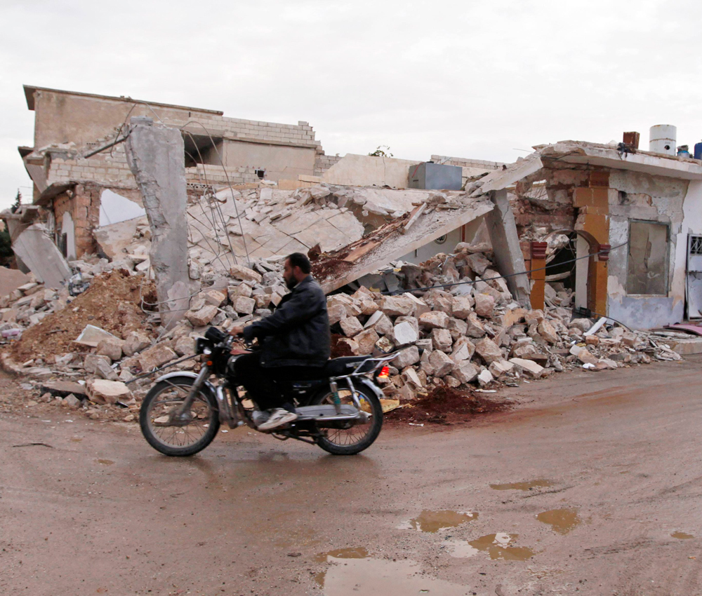 A civilian rides a motorcycle past a house damaged after shelling by forces loyal to President Bashar al-Assad, in al Atareb village in the western part of Aleppo November 9, 2012. Picture taken November 9. REUTERS