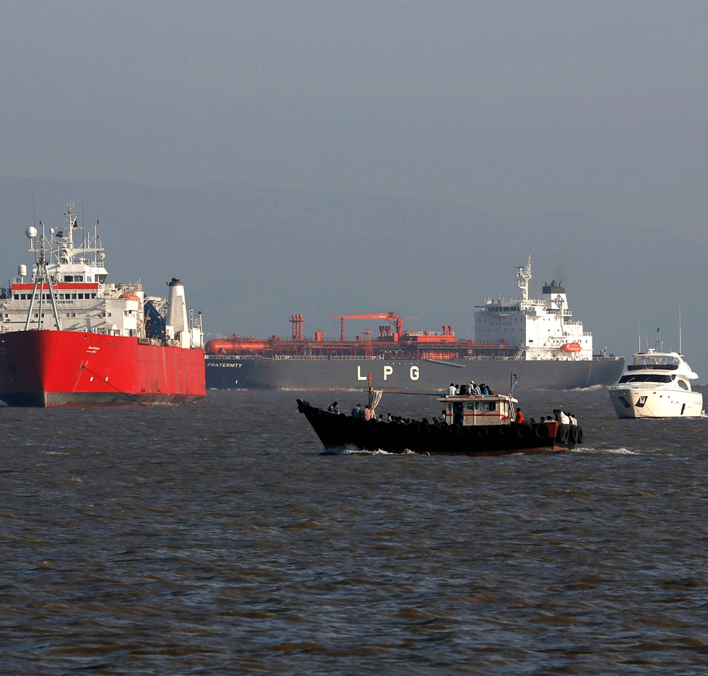 A small trawler passes in front of merchant vessels anchored outside the  port of Mumbai, April 9, 2013. India's exports fell 1.76 percent to  $300.6 billion in the fiscal year 2012/13, the first decline since  2009/10 and a driver of a record curren...