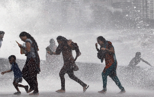 People enjoy along the Arabian Sea high tide in Mumbai, India, Thursday, July 25, 2013. AP photo