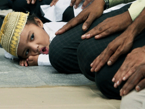 A  boy follows the elders offering Friday prayers on the road in  front of Tipu Sultan Mosque in Kolkata during the holy month of Ramadan.  PTI Photo