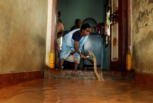 A woman trying to drain the rain water from her house after heavy rains in Chennai on Thursday. PTI Photo