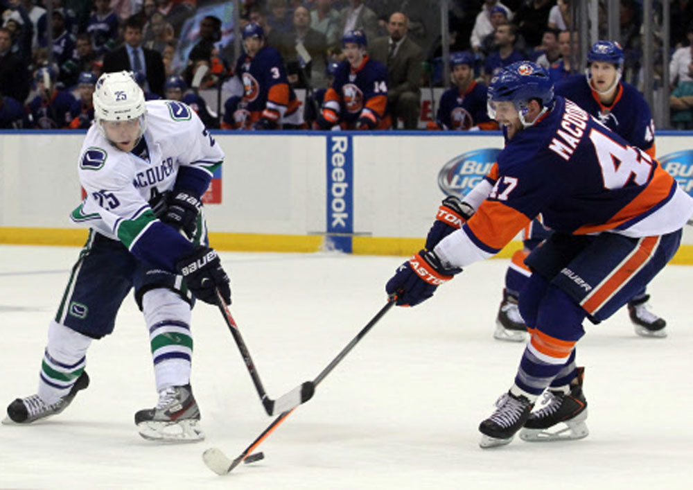Uniondale, NY, USA; New York Islanders defenseman Andrew MacDonald (47)  contests a shot by Vancouver Canucks center Mike Santorelli (25) during  the third period of a game at Nassau Veterans Memorial Coliseum. The  Canucks won 5-4 in overtime. Reute...