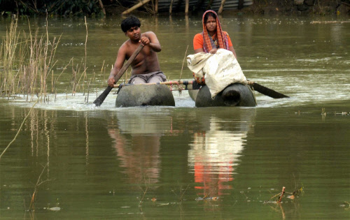 Villagers use small boat to move across a flooded village at flood-hit Ghatal City (125 km from Kolkata) in West Mednapore West Bengal on Tuesday. PTI Photo