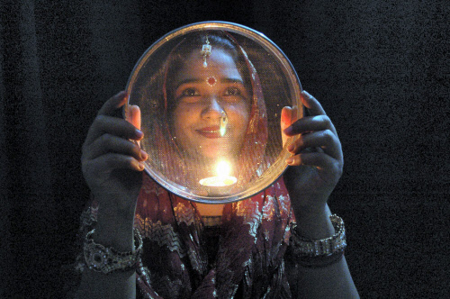 A married woman looks at the moon through a sieve before breaking her fast during 'Karva Chaut' celebrations in Mirzapur on Tuesday. PTI Photo
