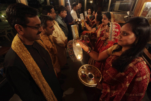 Married Hindu women prepares to perform rituals before their husbands during 'Karwa Chauth' festival, in Ahmadabad, Tuesday, Oct. 22, 2013. During this festival, married women fast throughout the day and offer prayers to the moon for the welfare, pro...