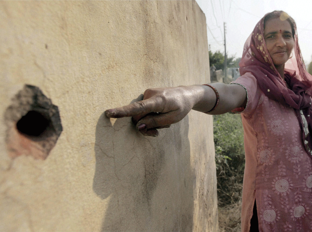 A villager pointing out the bullet mark on the wall of her house allegedly fired from Pakistan side at Pindi Charkhan village in Arnia sector of RS Pura about 45 km from Jammu on Wednesday. PTI Photo 