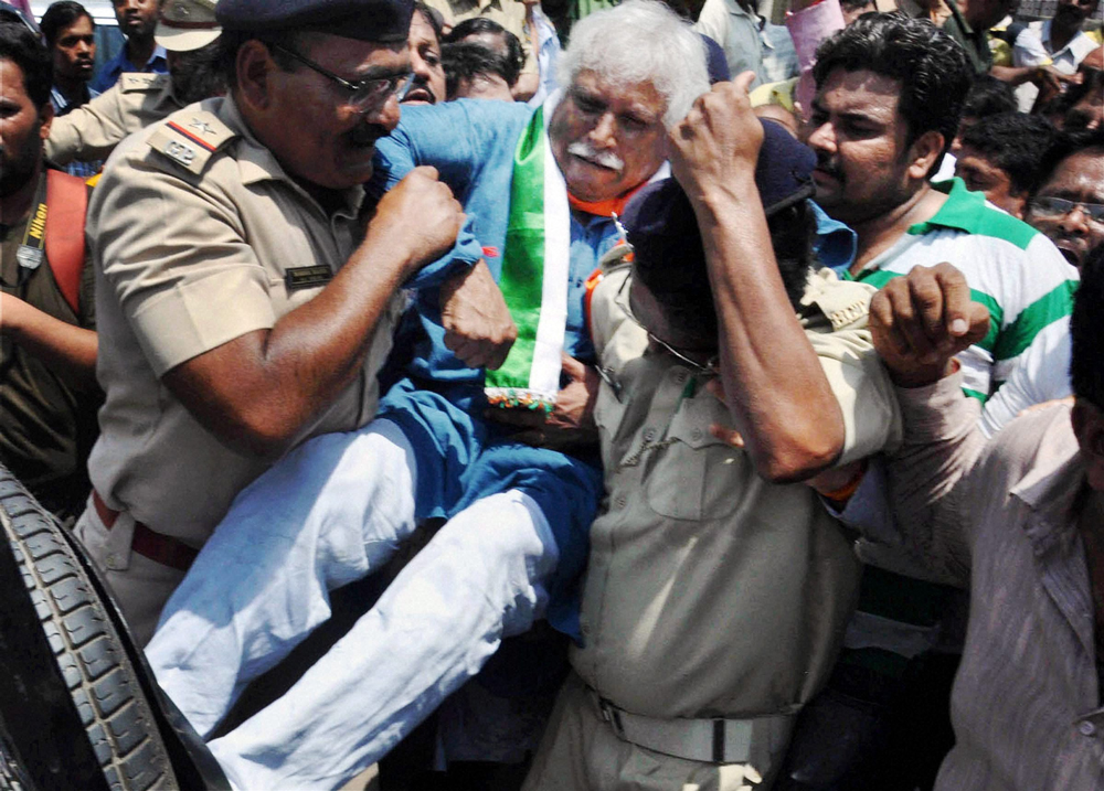 Vadodara : Police detain Congress candidate Madhunsudan Mistry for  tearing off posters of BJP candidate Narendra Modi from electric poles,  in Vadodara on Thursday. PTI Pho