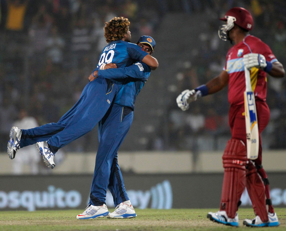 West Indies' Dwayne Smith (R) leaves the field as Sri Lanka's Lahiru Thirimanne congratulates bowler Lasith Malinga (L) over a successful dismissal during their semi-final match in the ICC Twenty20 World Cup at the Sher-E-Bangla National Cricket Stad...