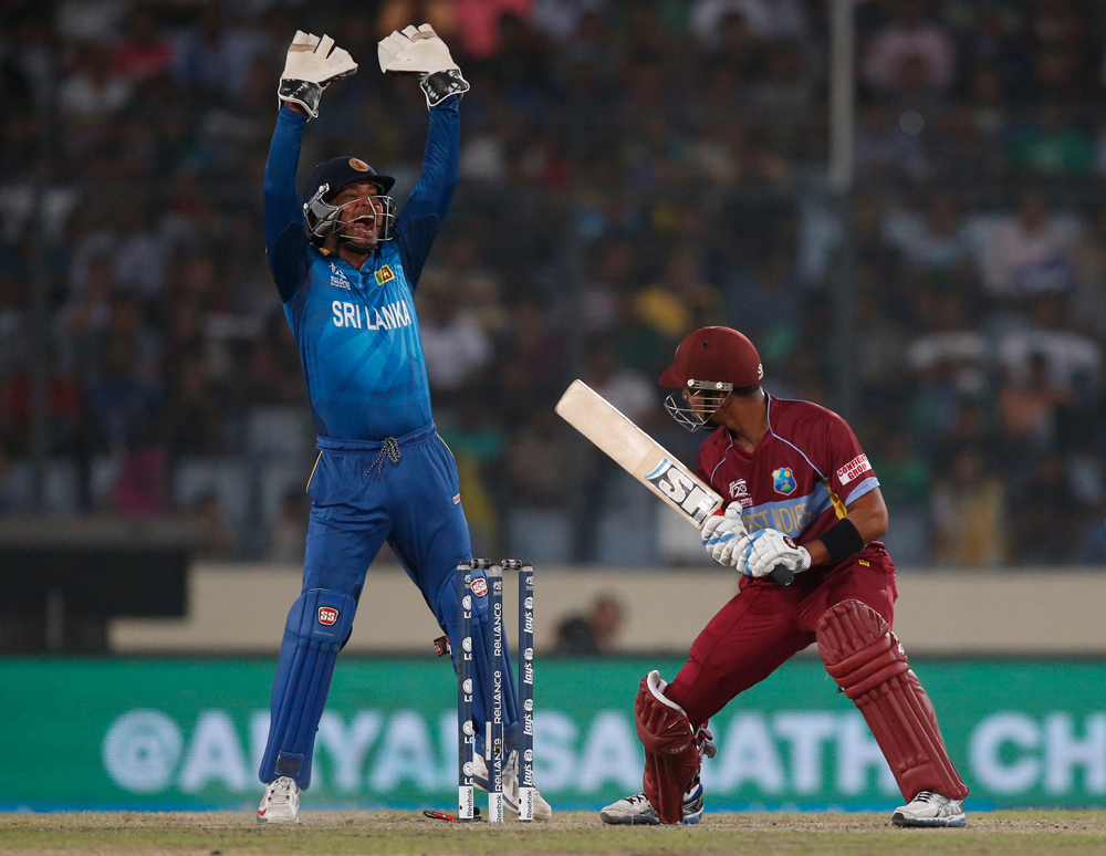 Sri Lanka's wicketkeeper Kumar Sangakkara, left, appeals successfully for the wicket of West Indies' batsman Lendl Simmons, right, during their ICC Twenty20 Cricket World Cup semi-final match in Dhaka, Bangladesh, Thursday, April 3, 2014. (AP Photo/A...