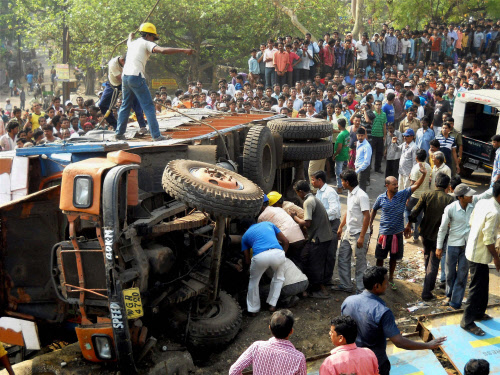 Local residents try to rescue people stuck after a truck overturned at Burdwan district in West Bengal on Thursday. PTI Photo