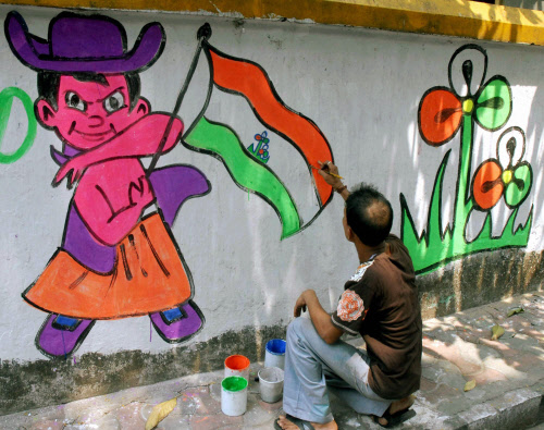 A Trinamool Congress worker makes a wall graffiti ahead of Lok Sabha election in Kolkata on Thursday. PTI Photo