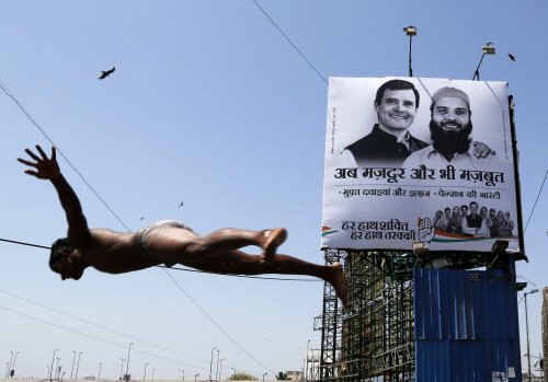 A boy dives into the Arabian Sea as India's ruling Congress party's election campaign banner featuring vice president Rahul Gandhi,is erected behind in Mumbai, AP Photo