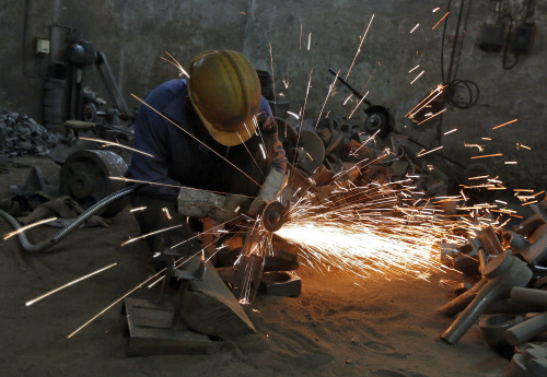 A worker grinds a metal shaft metal used in water pumps at a manufacturing unit on the outskirts of the western Indian city of Ahmedabad. Indian factory activity expanded at a slightly faster pace in May, while input prices rose at their slowest rate...