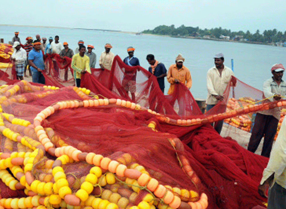 Fishermen adjusting their fishing net at Bunder, Mangalore on Monday. DH photo 