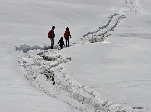 A tourist couple with their kid at Gulmarg ski resort in district Baramulla on Wednesday. PTI Photo