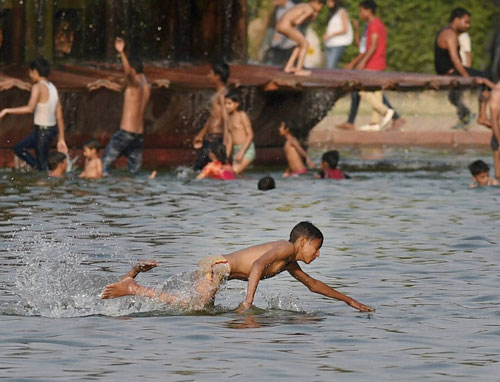 Children enjoy in the waters of a fountain to beat the heat at India Gate as the mercury rises in New Delhi on Sunday.PTI Photo