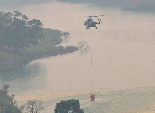 Indian Air Force Helicopter collects water from Koteshwar dam during the rescue operation to control fire which broke out in the forests of Garhwal range in Srinagar, Uttrakhand on Sunday. PTI Photo