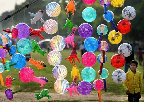 A boy admires plastic balls put up for sale at India Gate lawns in New Delhi on Sunday. PTI Photo