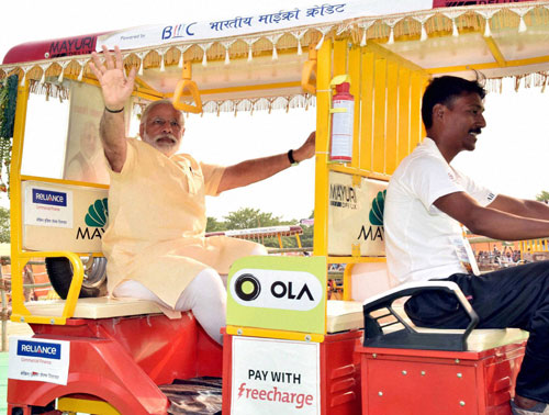  Prime Minister Narendra Modi rides in an E rickshaw during distribution of E rickshaws in Varanasi on Sunday. PTI Photo