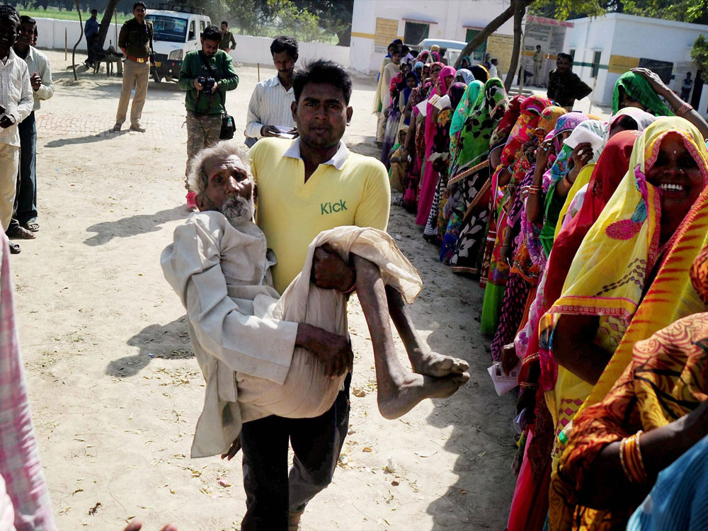 A boy carrying his grand father for casting during the 4th phase of assembly elections in Allahabad on Thursday. PTI Photo