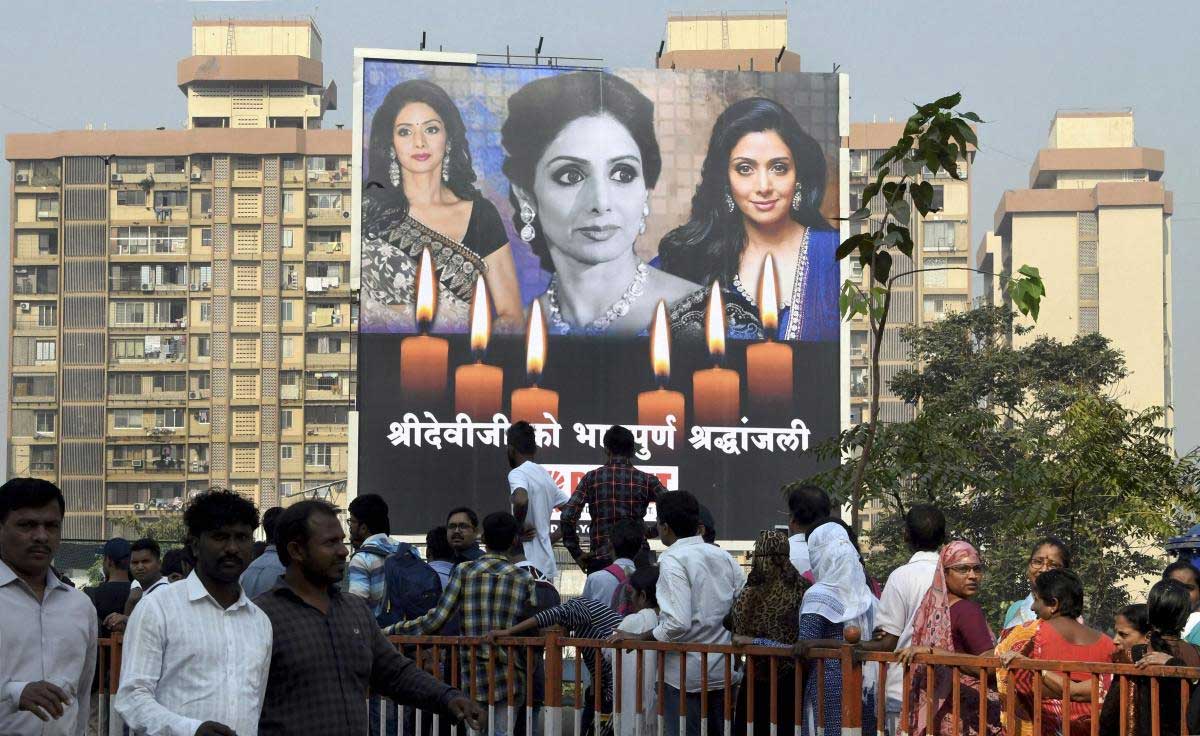 Fans gather near a hoarding of veteran actor Sridevi to pay homage, in Mumbai on Wednesday. PTI Photo 