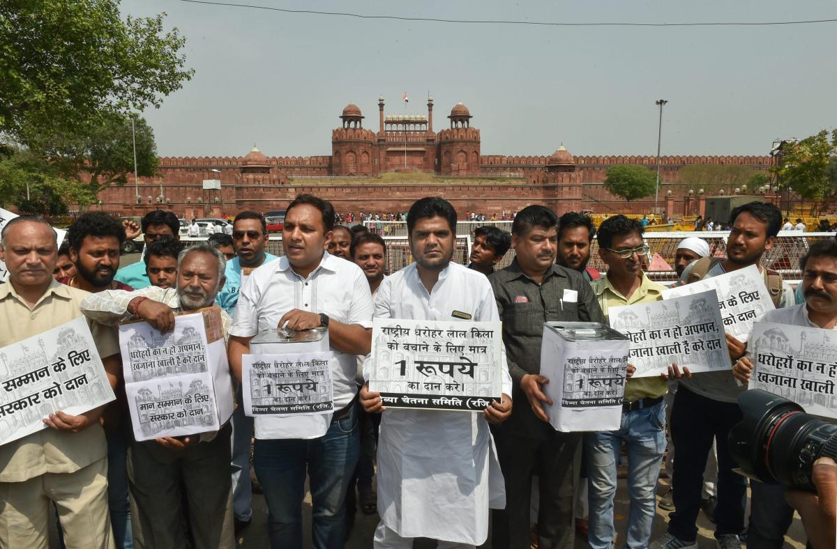 Members of Divya Chetna Samiti display placards at a protest to save Red Fort in the view of the recently signed MoU between Dalmia Bharat and Ministry of Culture for upkeeping the historic monument, in New Delhi on Wednesday. PTI Photo