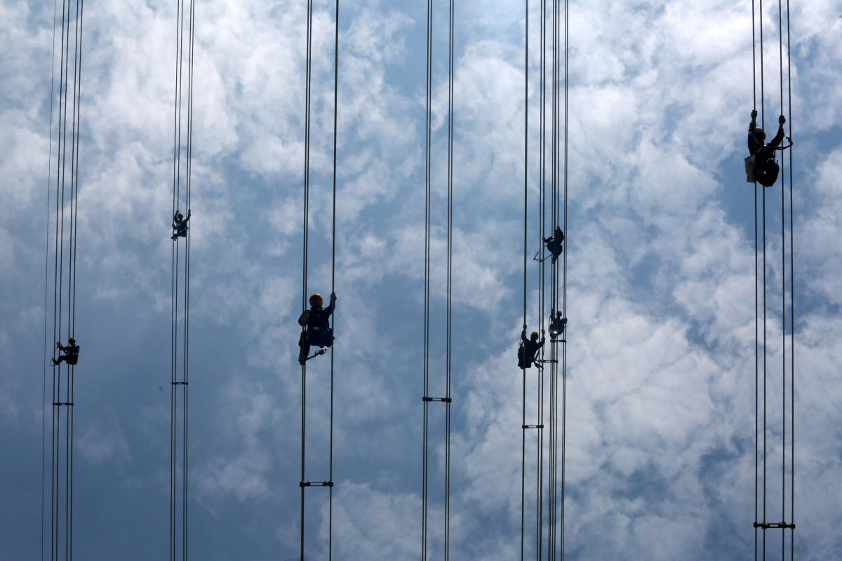 Workers of grid operator China Southern Power Grid inspect power cables connecting transmission towers in Dongguan, Guangdong province, China May 29, 2018. Picture taken May 29, 2018. REUTERS/Stringer