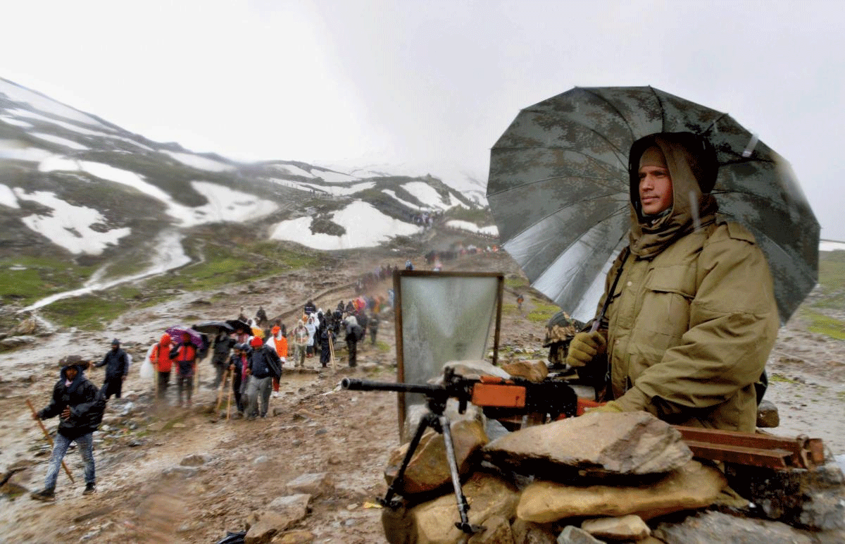 A security person keeps vigil as pilgrims walk towards the holy cave shrine of Amarnath, in Pahalgam on Friday, July 6, 2018. (PTI Photo)