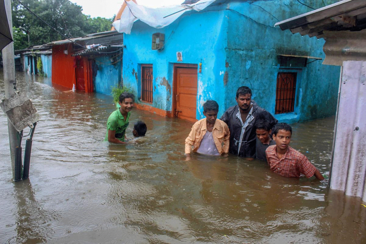 People make thier way through a waterlogged street after heavy rains, in Kalyan, Mumbai on Saturday, July 7, 2018. PTI Photo