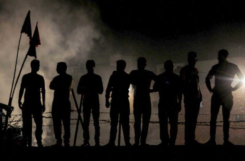 People stand on a wall near the site of a train accident, in the backdrop of smoke from burnt effigies of demon King Ravana, at Joda Phatak in Amritsar on Friday. Officials said at least 60 bodies have been found and many more injured have been admitted to a government hospital after the accident near the site of Dussehra festivities. PTI Photo